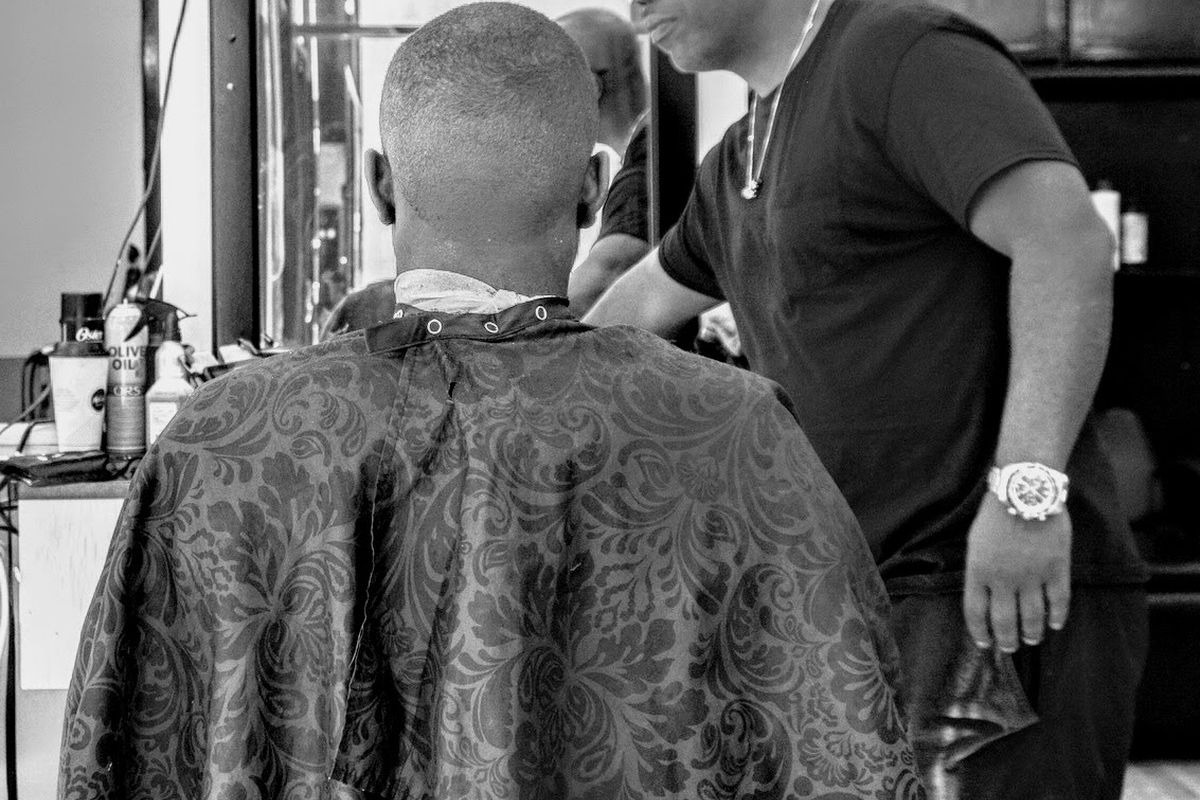 The back of a fresh fade, clippers still in the barber's hand